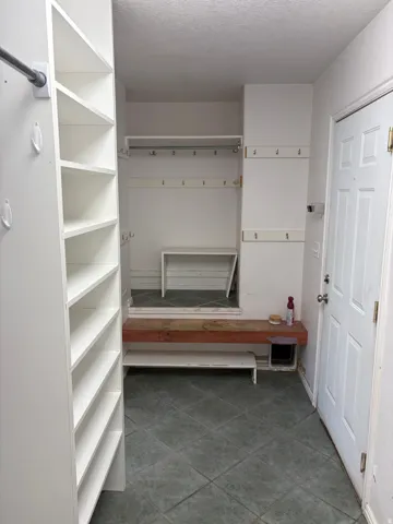 Entryway featuring a white paneled door, built-in shelving, storage hooks, and square tile flooring