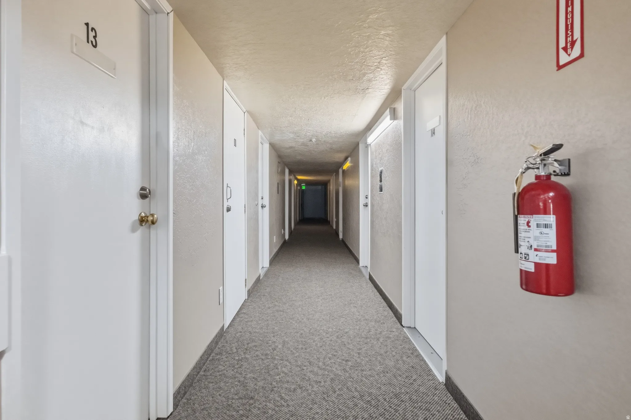 Hallway with light-colored walls and a textured ceiling