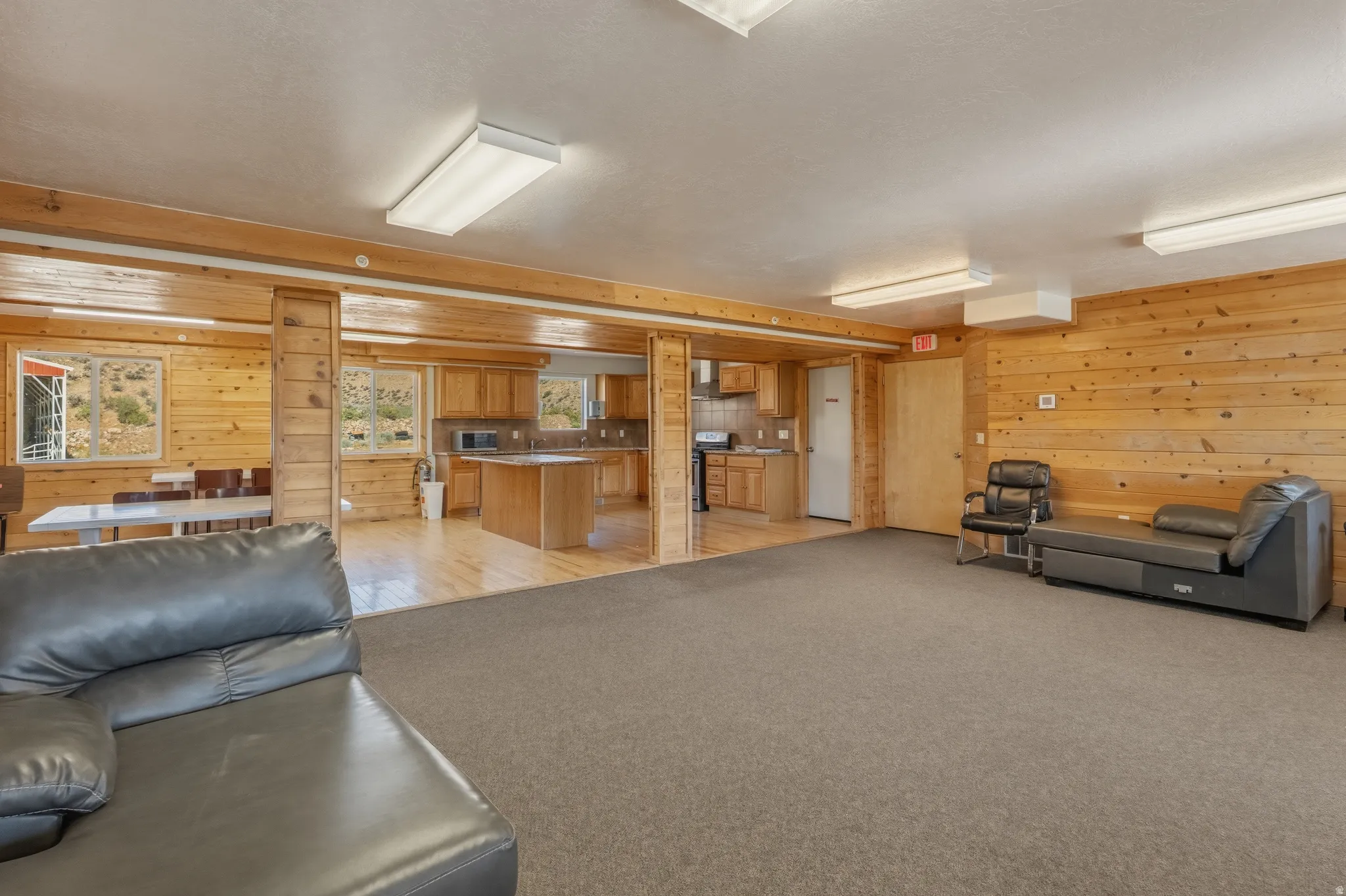 Open-concept living area featuring wood-finish paneling, light wood-finish flooring, and recessed lighting