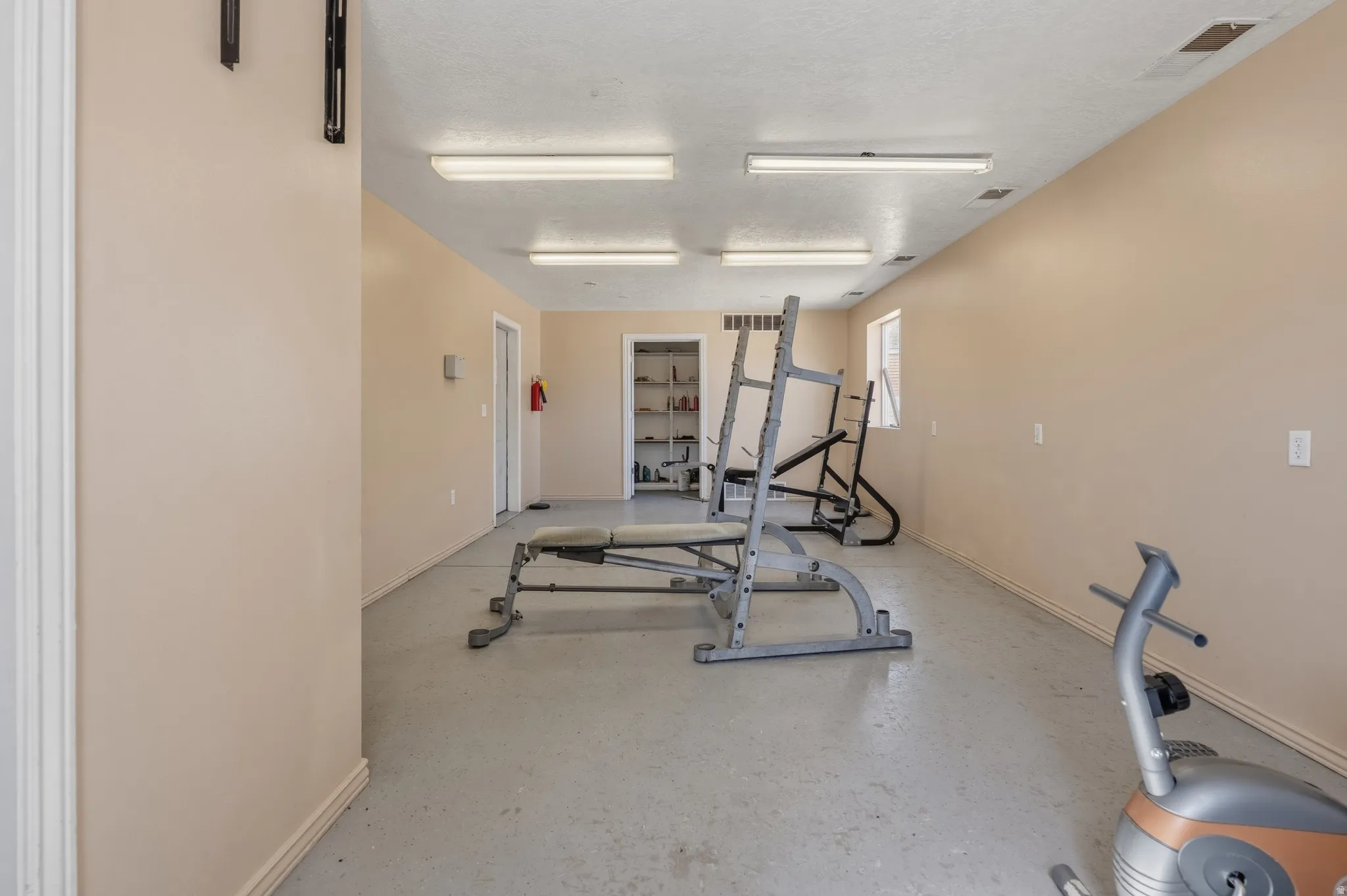 Spacious interior room featuring light beige walls and a gray speckled floor
