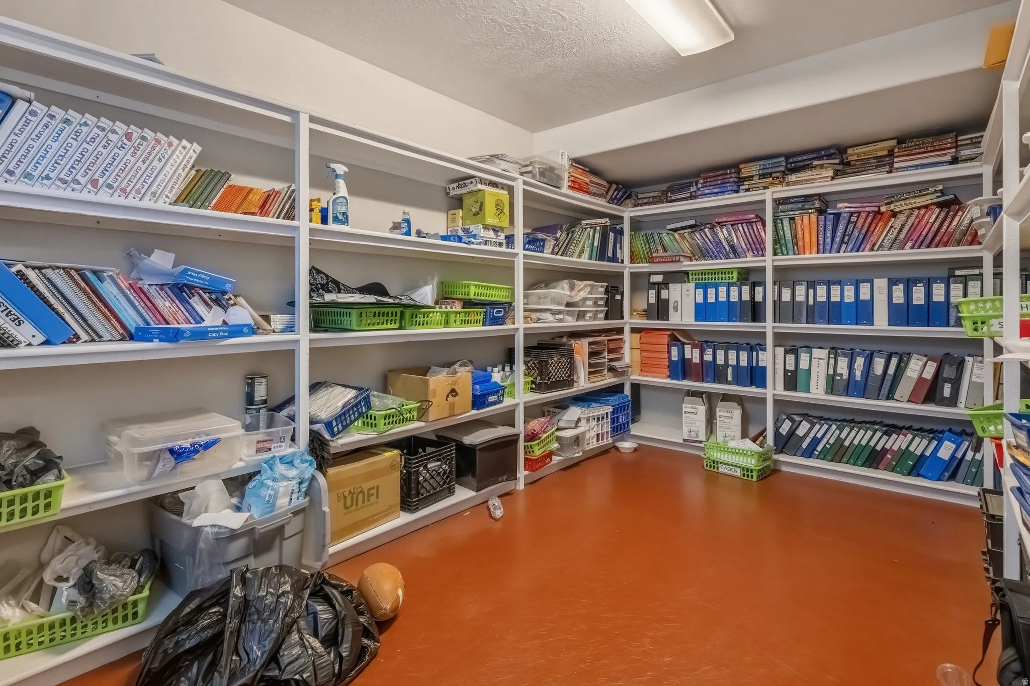 Dedicated storage room featuring extensive built-in shelving, durable flooring, and recessed lighting
