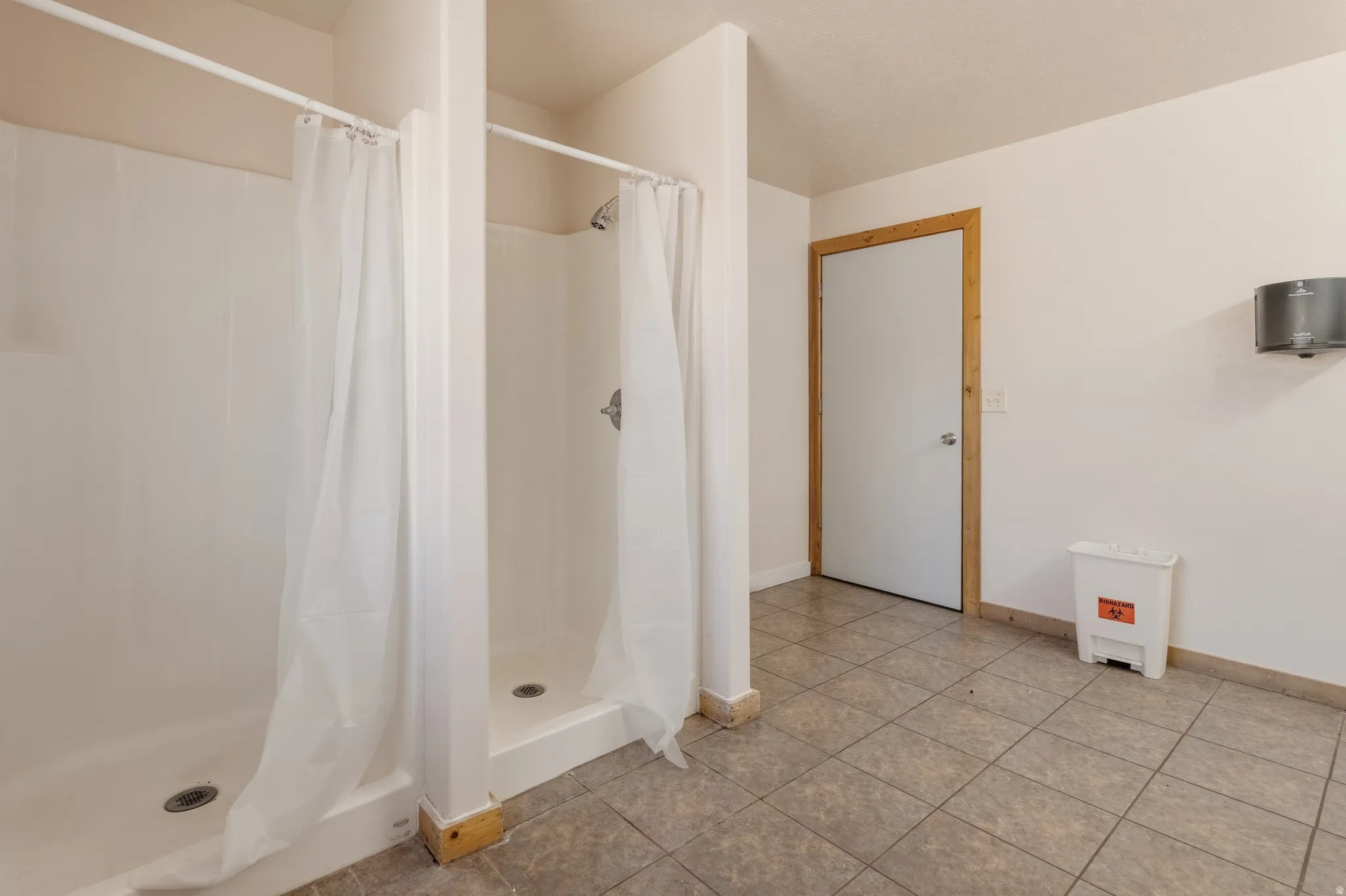 Utility room with multiple shower stalls featuring integrated shelving and individual shower curtains
