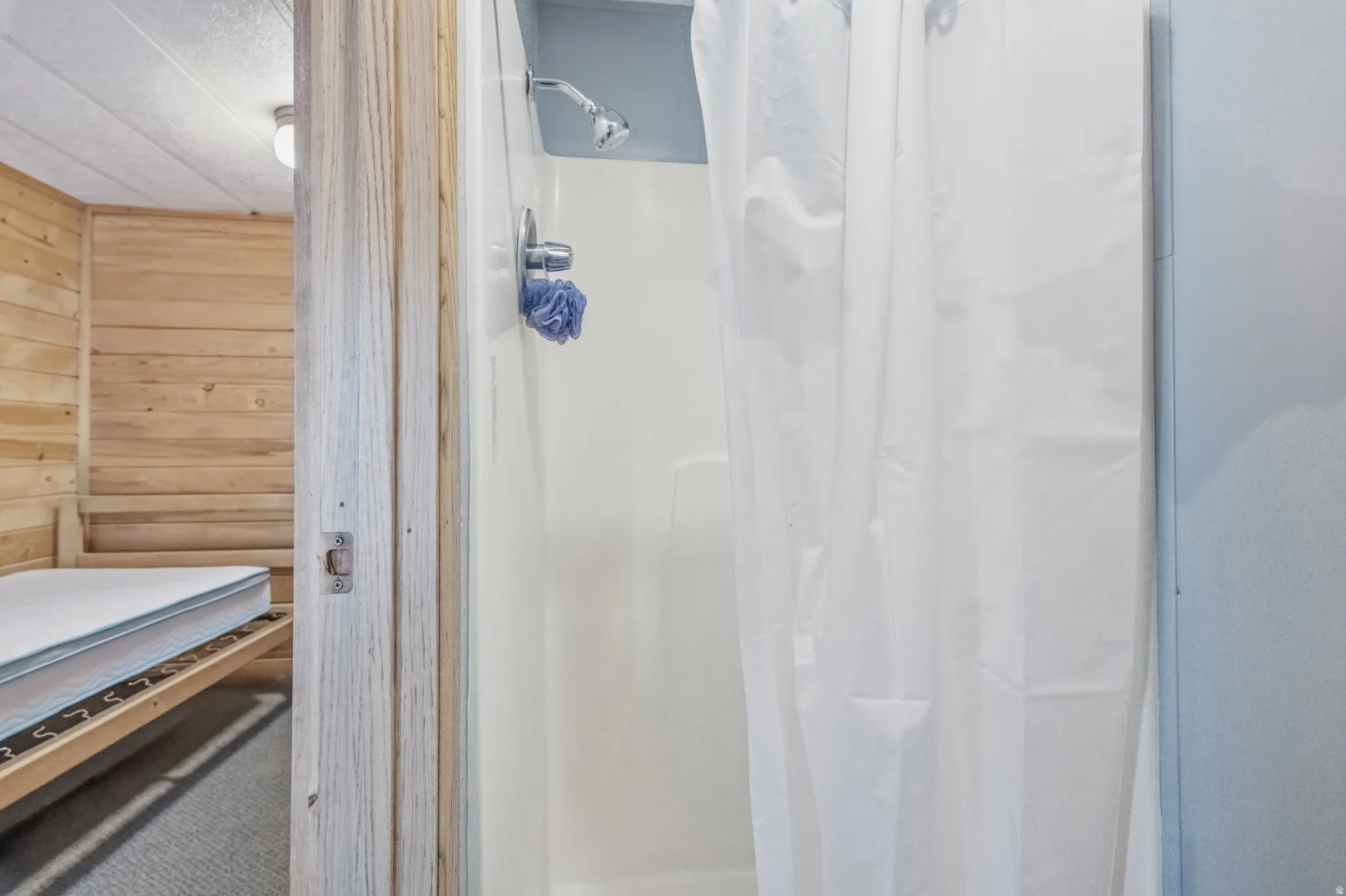 White shower enclosure with a chrome shower head and handle