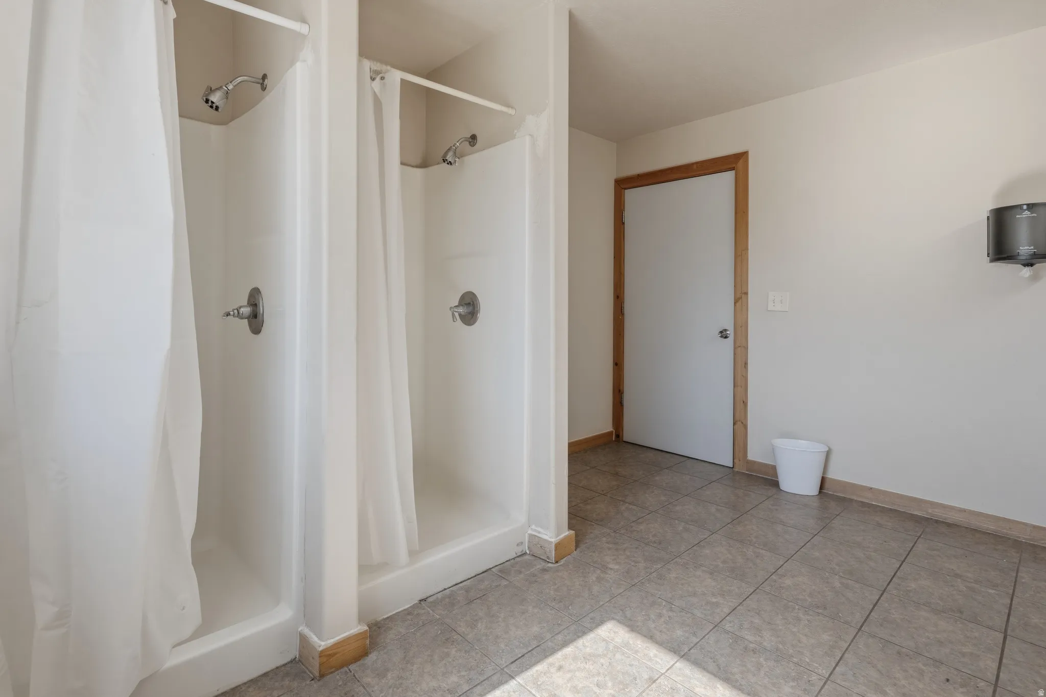 Two individual shower stalls with white liners and shower curtains