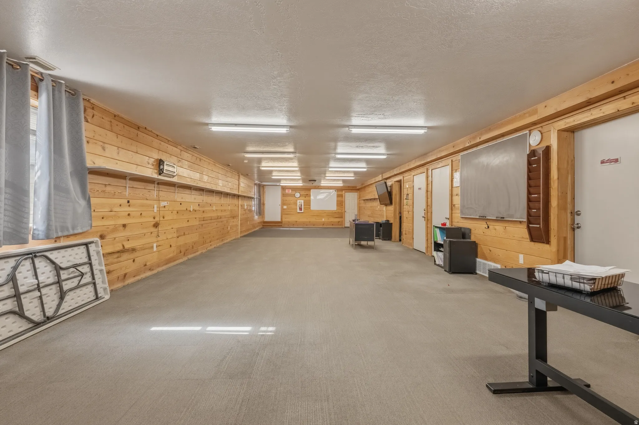 Spacious room featuring wood paneling, multiple doors, and recessed lighting
