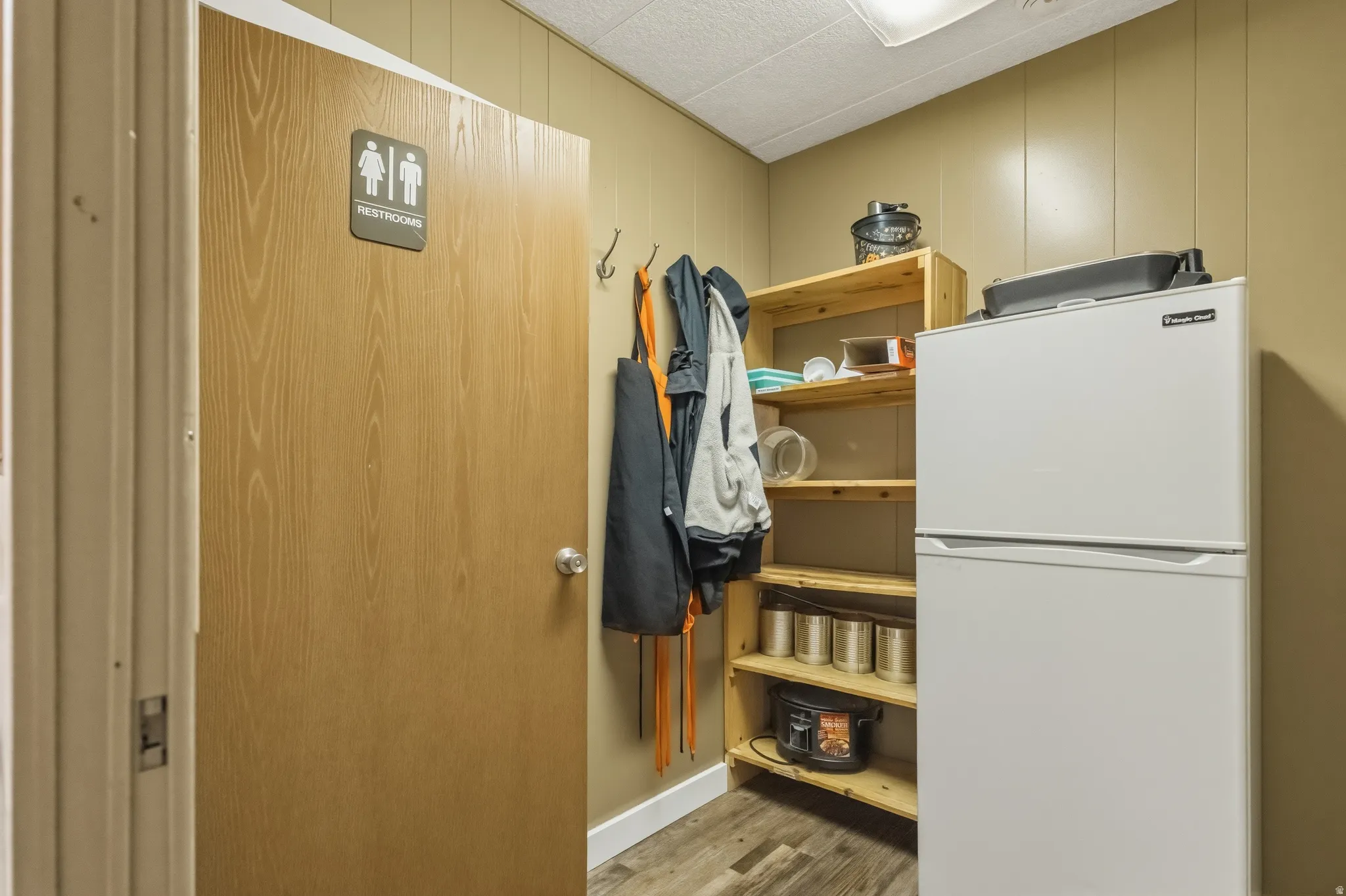 Wood-finish door with a silver knob and restroom signage
