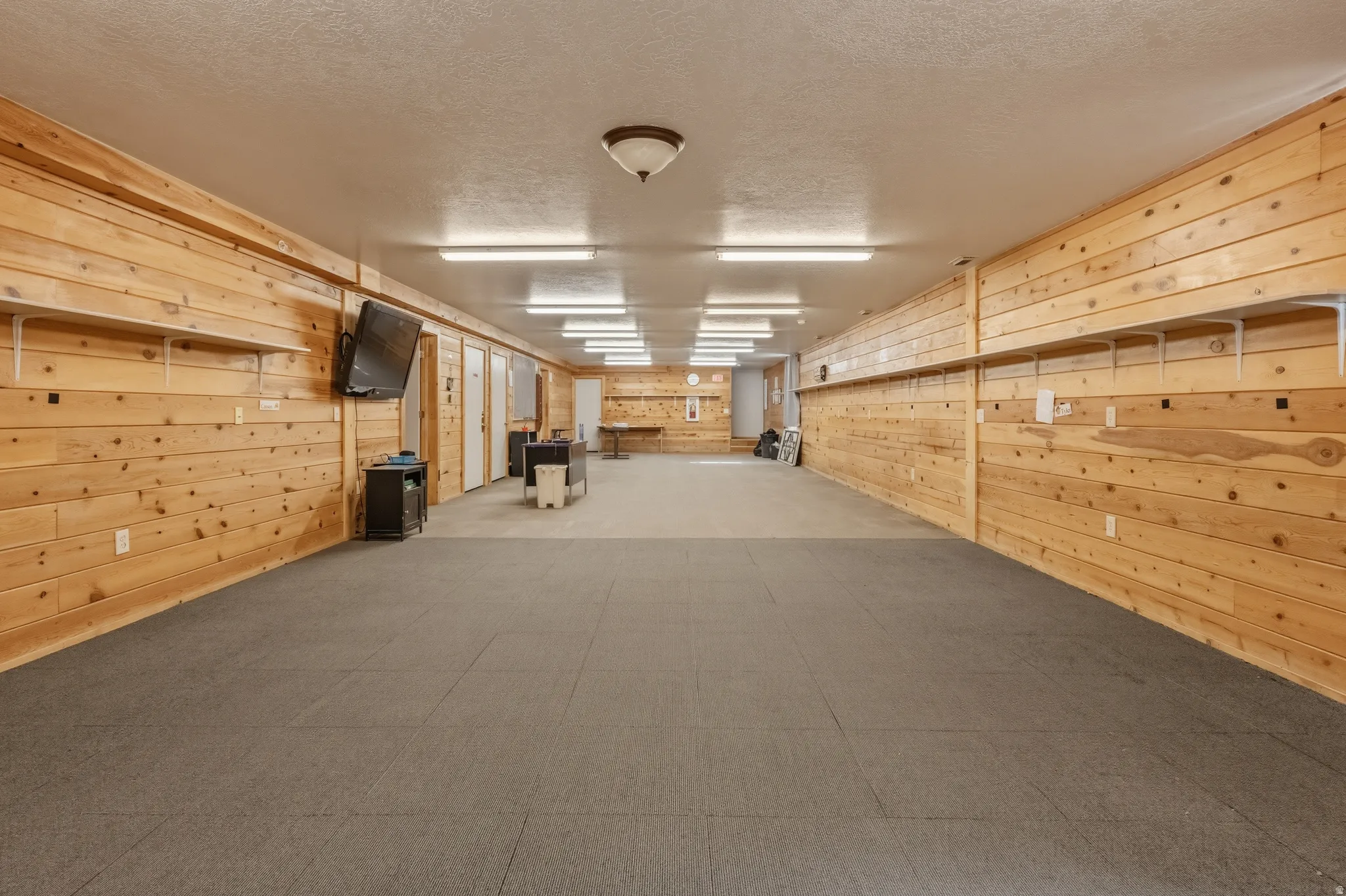 Expansive room featuring wood-paneled walls and a combination of carpet and hard surface flooring