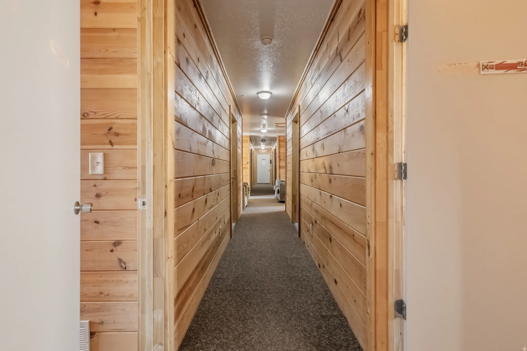 Hallway featuring wood plank walls, recessed lighting, and carpet flooring