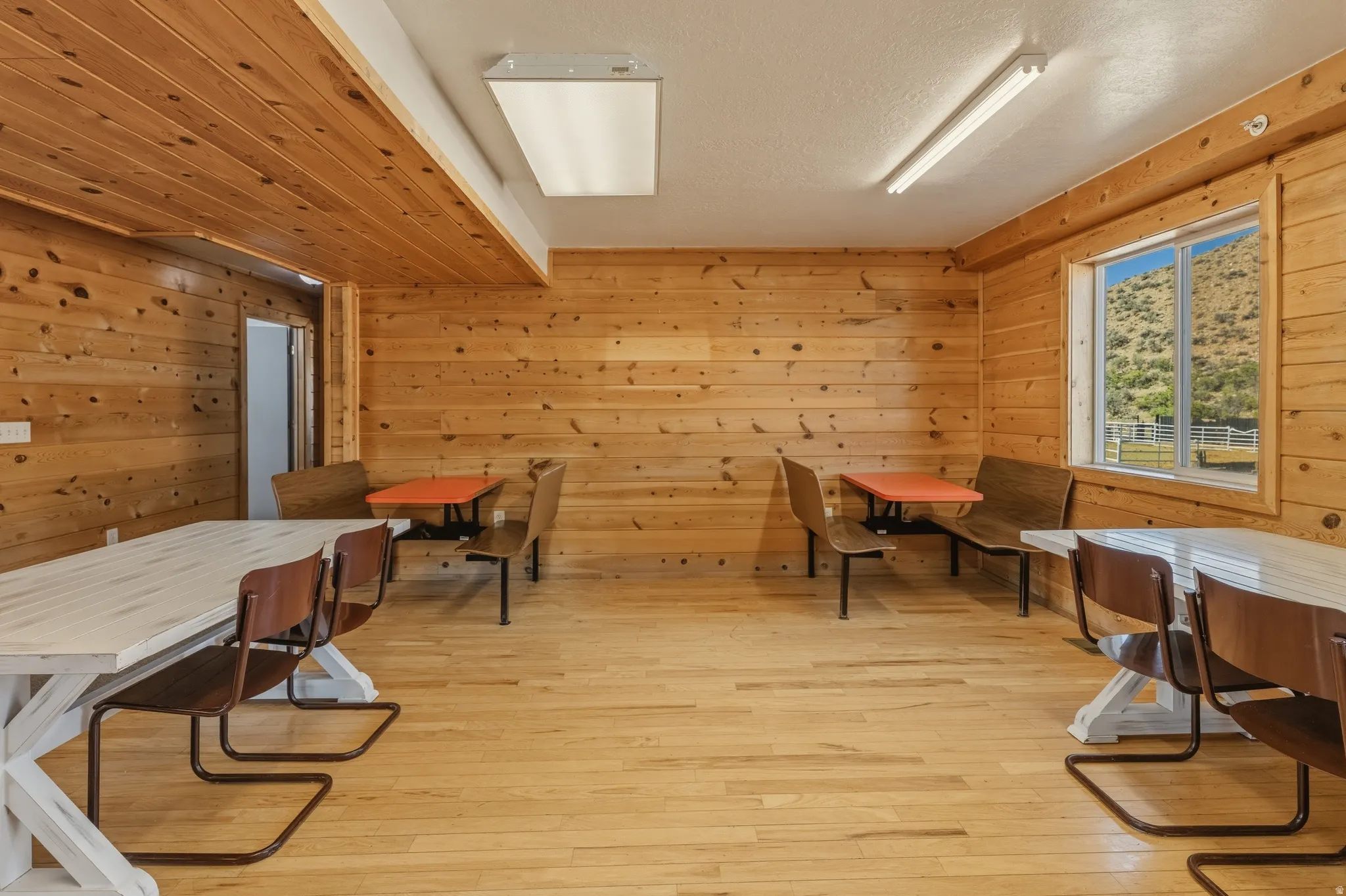 Interior room featuring wood-finish wall and ceiling panels, wood-finish flooring, recessed lighting, and a large window