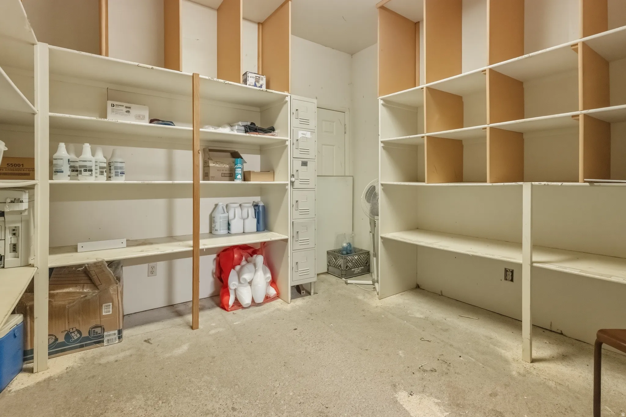 Spacious utility room featuring extensive built-in shelving, durable concrete flooring, and a white paneled door