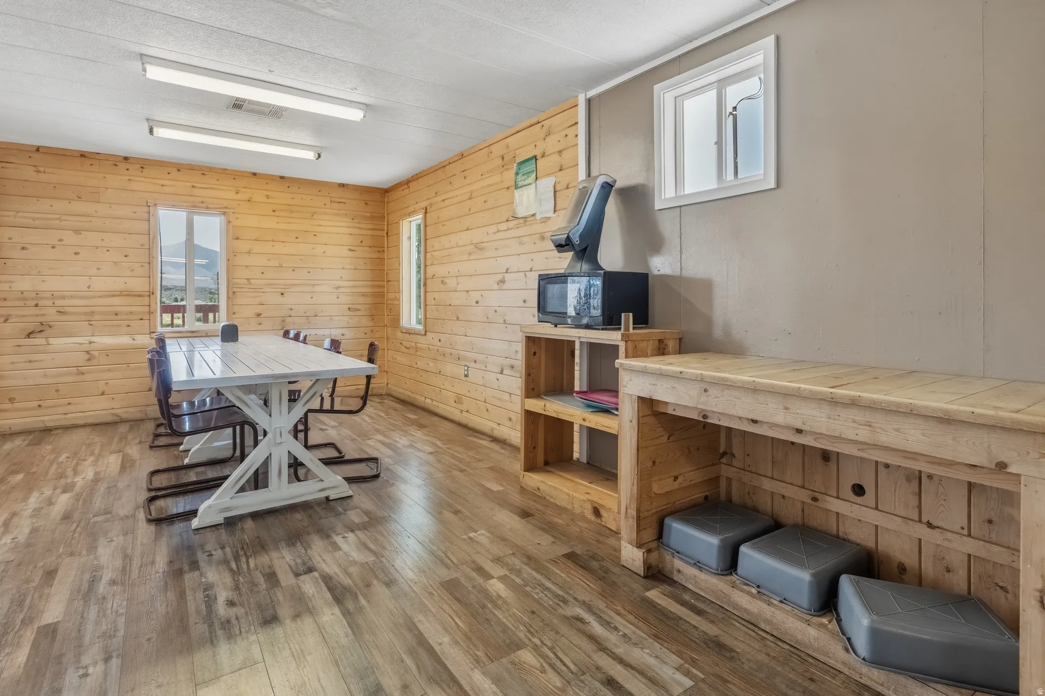Spacious room featuring wood-finish flooring, light wood paneling, and multiple windows