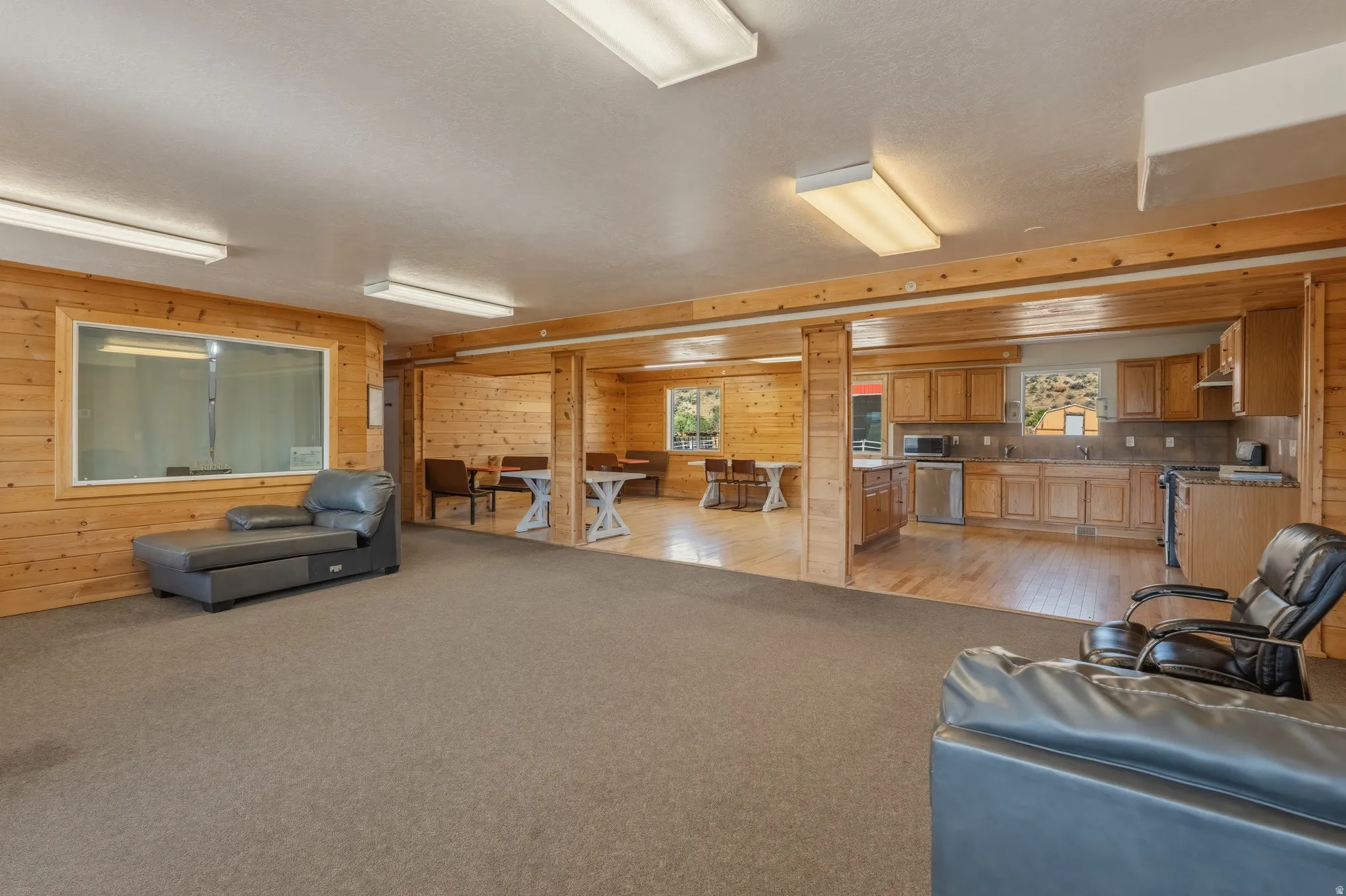 Expansive open-concept room featuring wood-paneled walls and ceiling, recessed lighting, and a large carpeted area