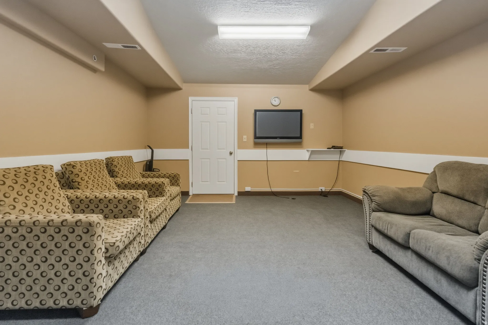 Finished lower level featuring neutral wall tones, gray carpeting, a built-in wall shelf, and recessed lighting