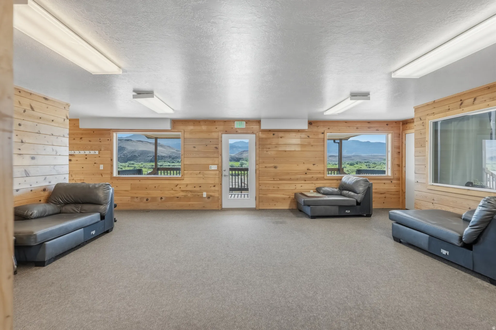 Spacious room featuring wood-finish wall paneling and neutral carpeting