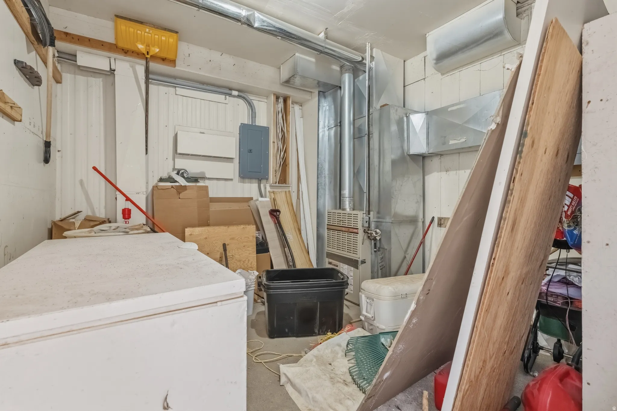 Utility room featuring exposed ductwork, a wall-mounted electrical panel, and a furnace unit