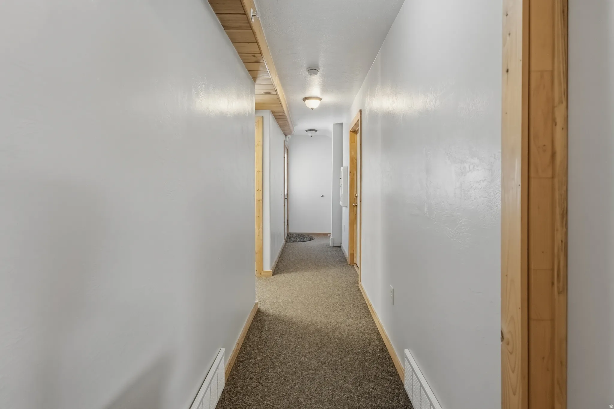 Corridor featuring light gray walls, wood-finish trim, and recessed ceiling lighting