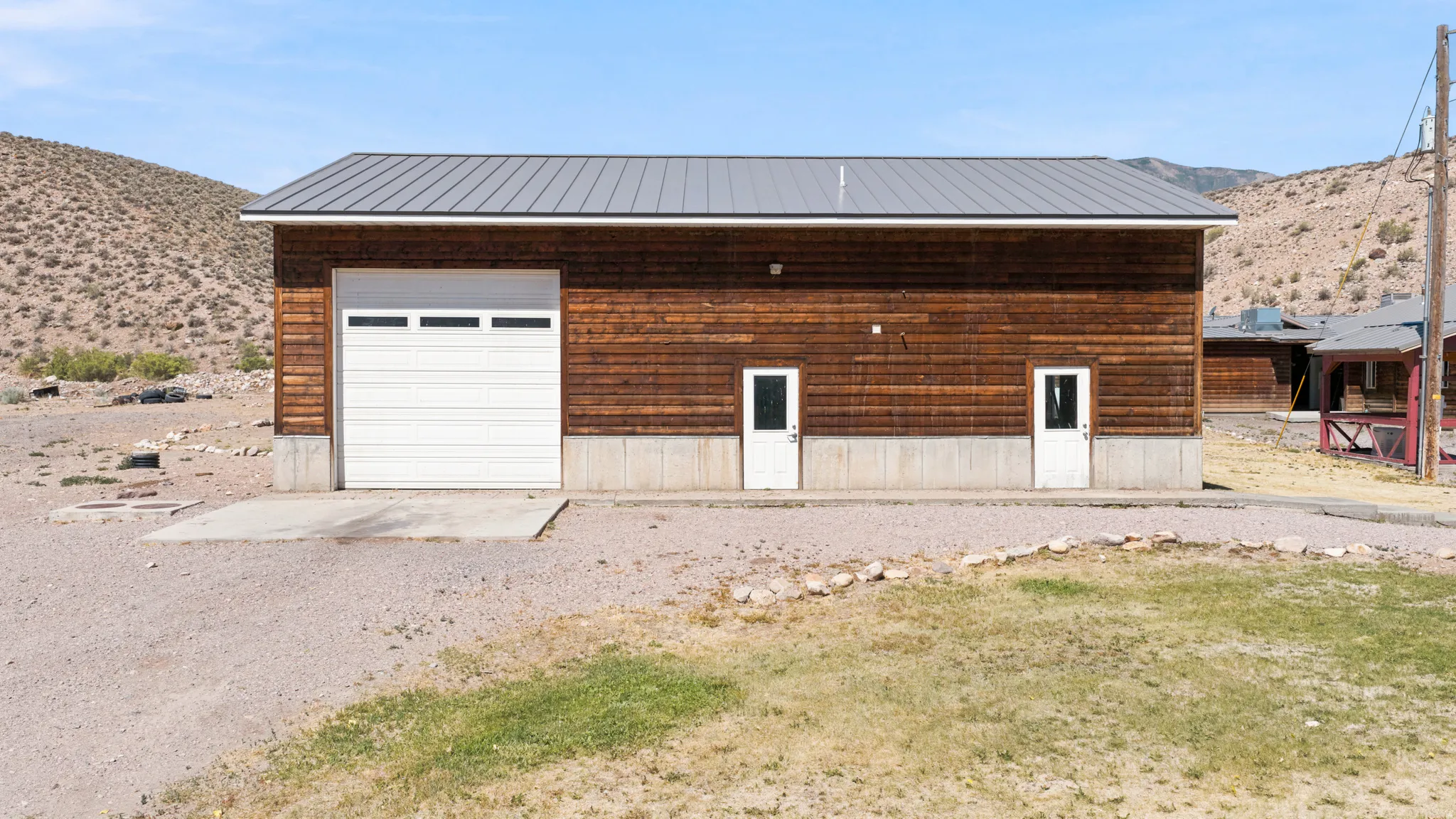 Utility building featuring a metal roof, wood-finish siding, and a concrete foundation