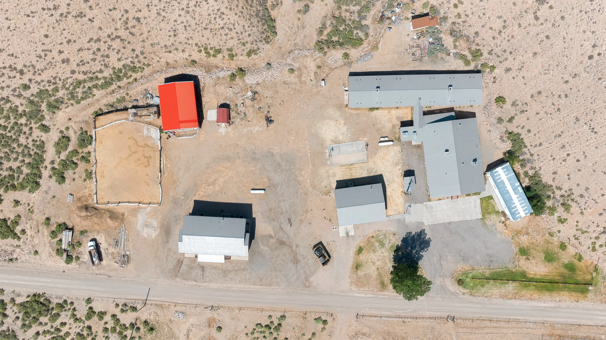 Expansive property featuring multiple structures, including a primary residence with a gray roof, a large red-roofed building, and several smaller outbuildings