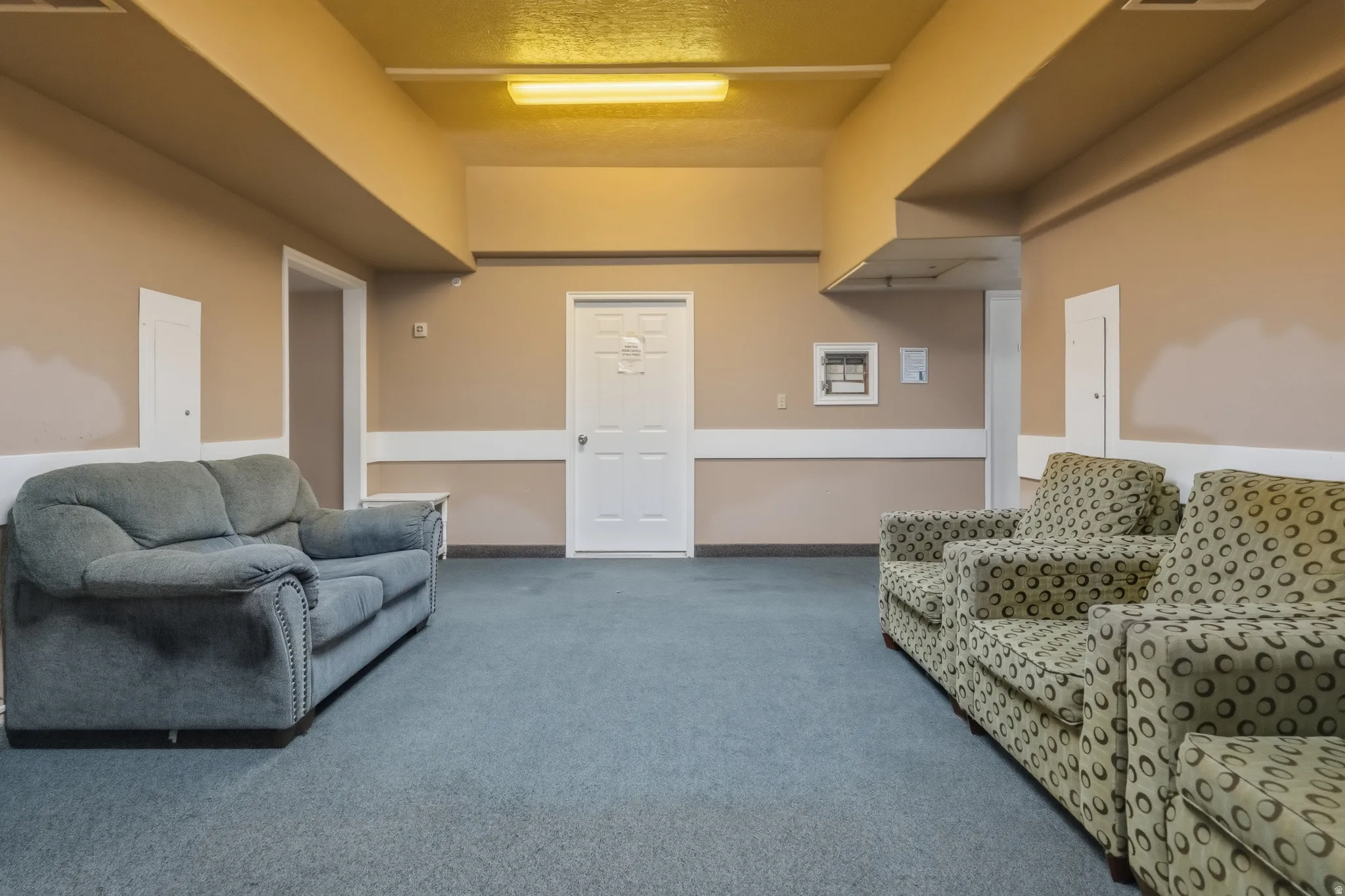 Spacious interior area featuring neutral wall tones, blue carpeting, and multiple doorways