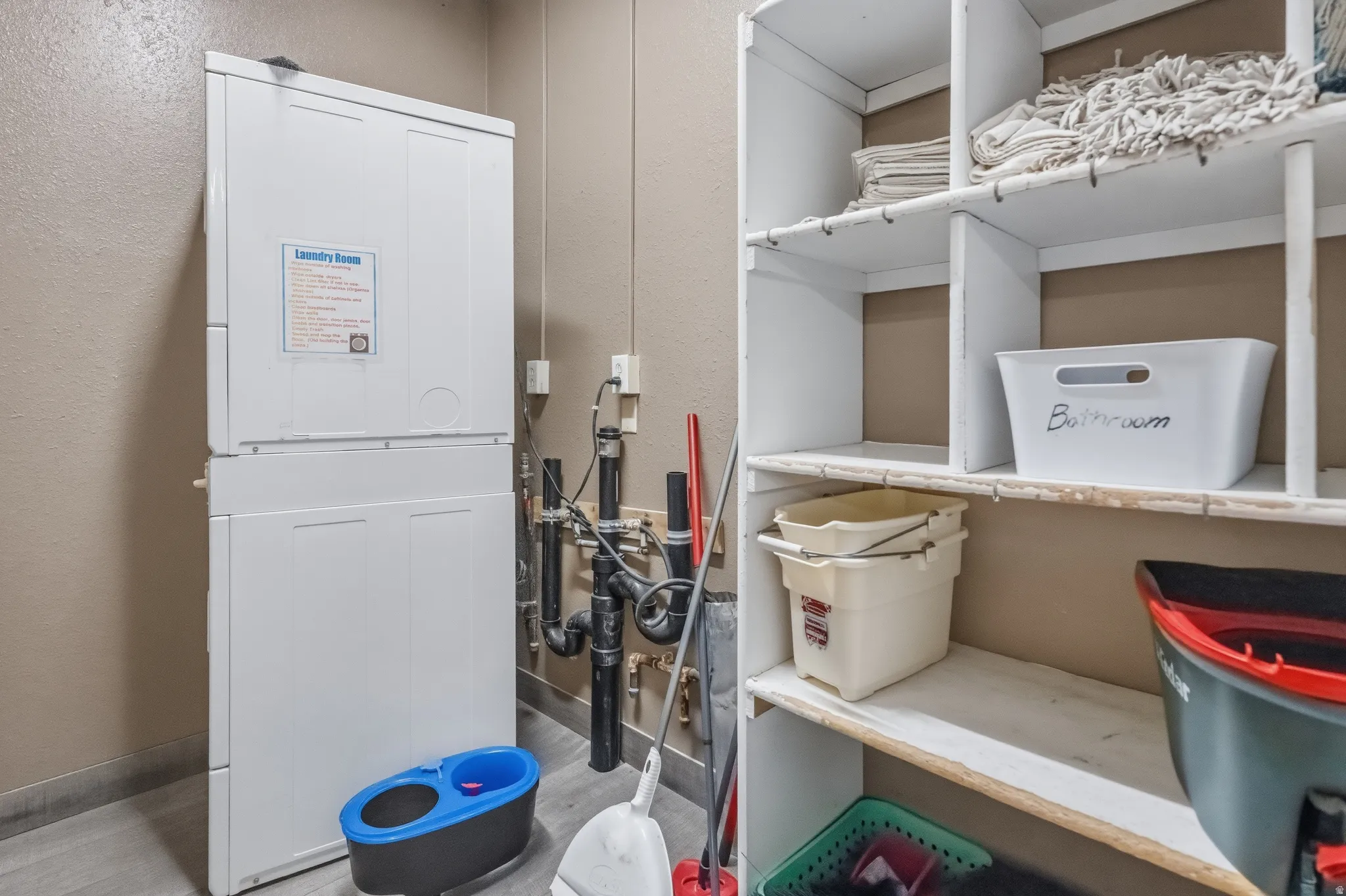 Dedicated laundry area featuring a stacked white appliance unit
