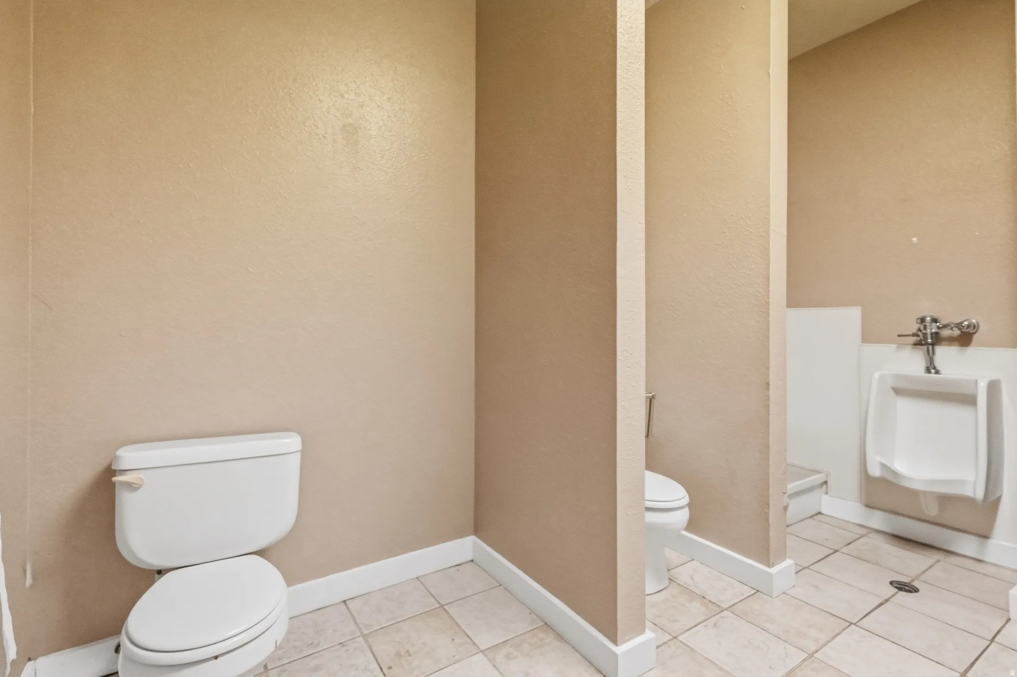 Bathroom featuring neutral-toned walls, white baseboards, and square floor tiles