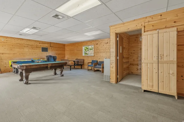 Recreational space featuring extensive wood paneling, recessed lighting, drop ceiling, and light gray carpeting