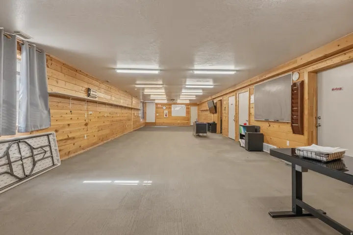 Spacious room featuring wood paneling, multiple doors, and recessed lighting