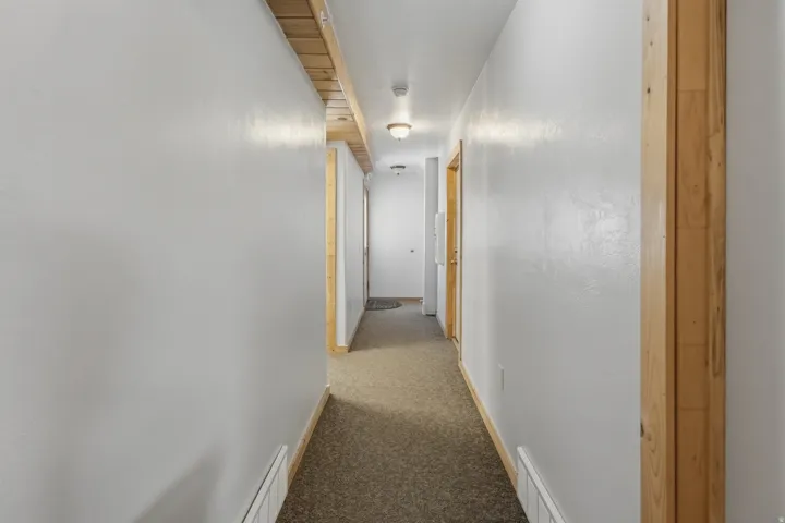 Corridor featuring light gray walls, wood-finish trim, and recessed ceiling lighting