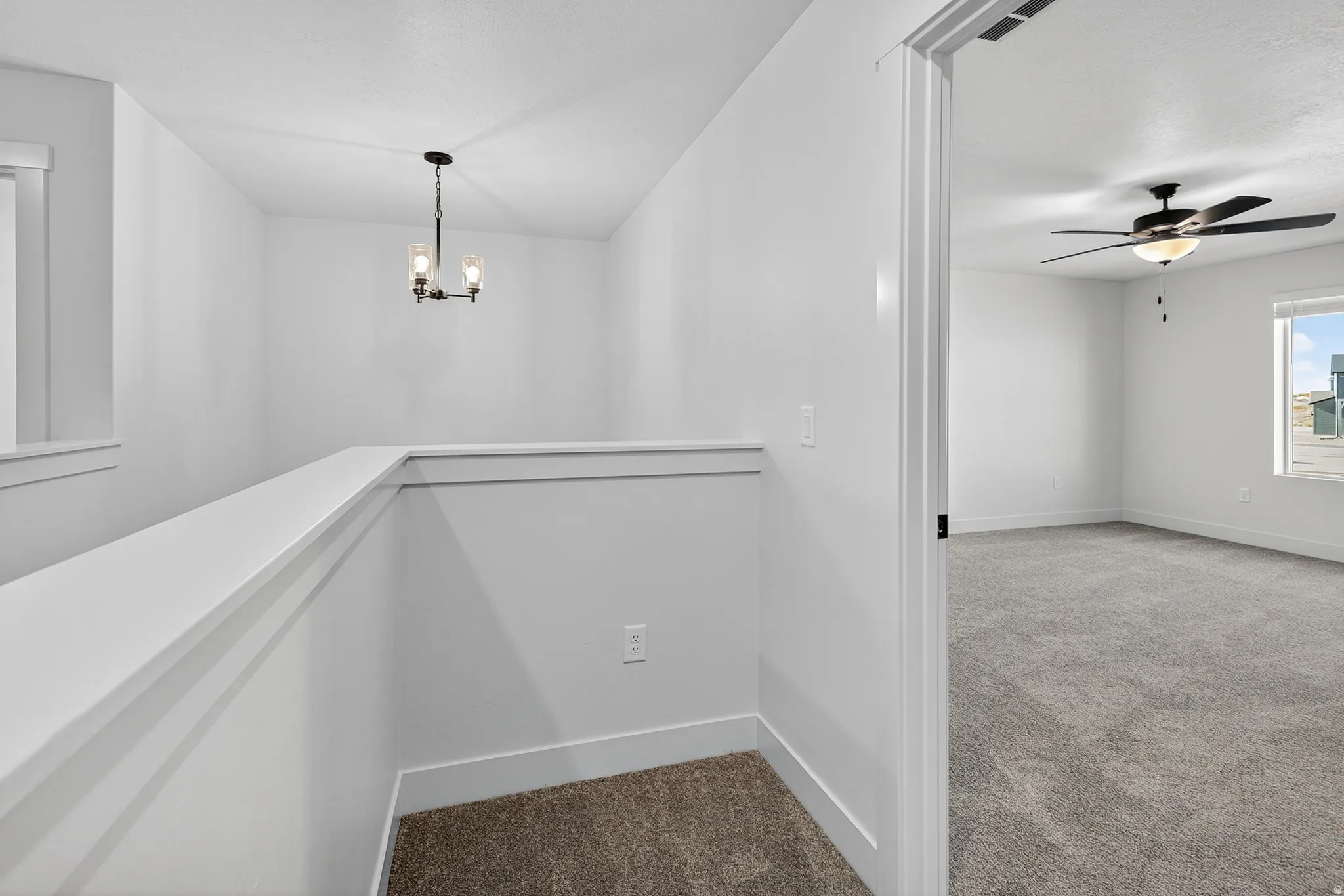 Upper-level landing featuring a contemporary chandelier, white wall finishes, and a neutral carpeted floor