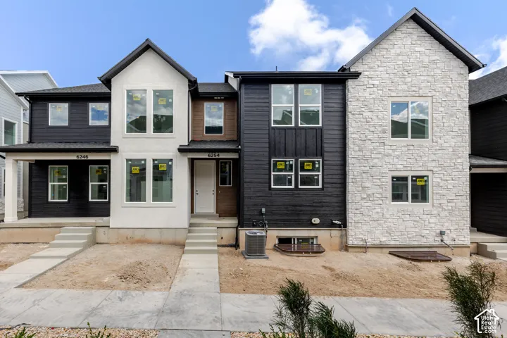 Contemporary facade featuring a mix of white stucco, dark vertical and horizontal siding, and stone veneer accents