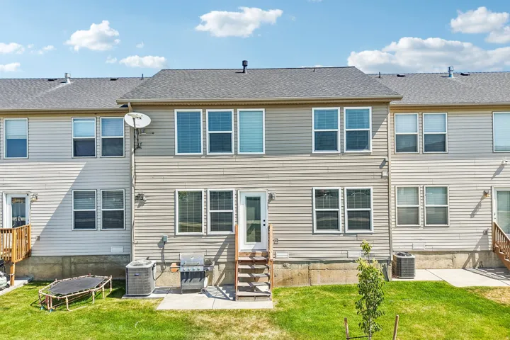 Rear exterior featuring horizontal siding, multiple windows, and a ground-level patio