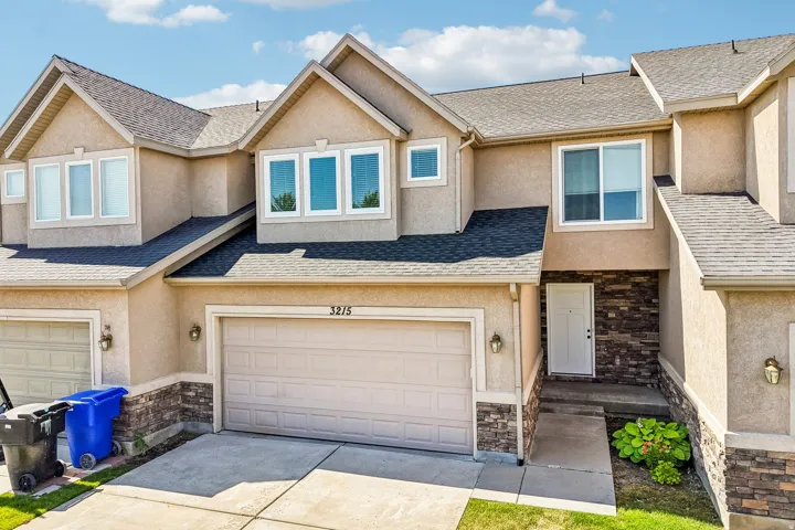 Stucco exterior featuring a single-car garage and stone veneer accents