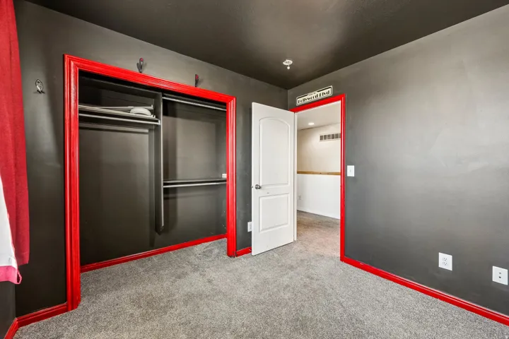 Room featuring dark gray walls, red trim, and gray carpet flooring