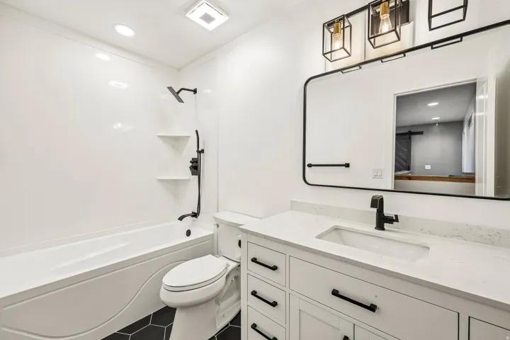 Bathroom featuring a white vanity with an integrated sink, black hardware, and a quartz-finish countertop