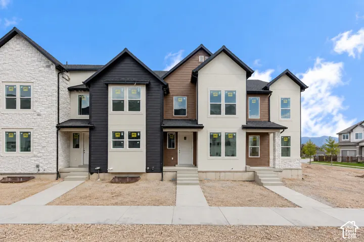 Contemporary townhomes featuring multi-textured facades, gabled roofs, and prominent window installations