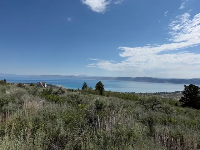 Expansive lakefront property featuring a distant home with a gabled roofline and multiple windows