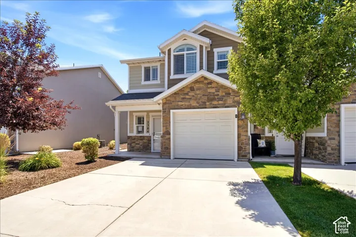 Stone and siding exterior with a covered entry, an arched window, and an attached garage