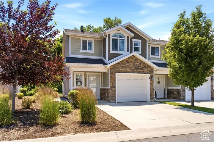 Two-story residence featuring stone and siding exterior, arched window, and attached garage