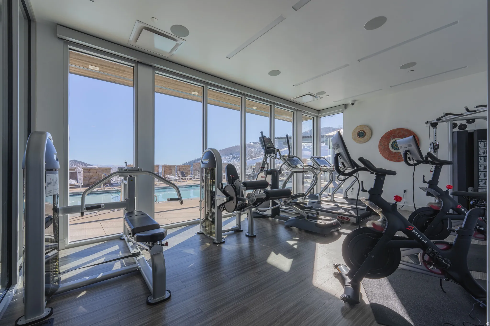 Fitness center featuring floor-to-ceiling windows, wood-finish flooring, recessed lighting, and integrated sound system
