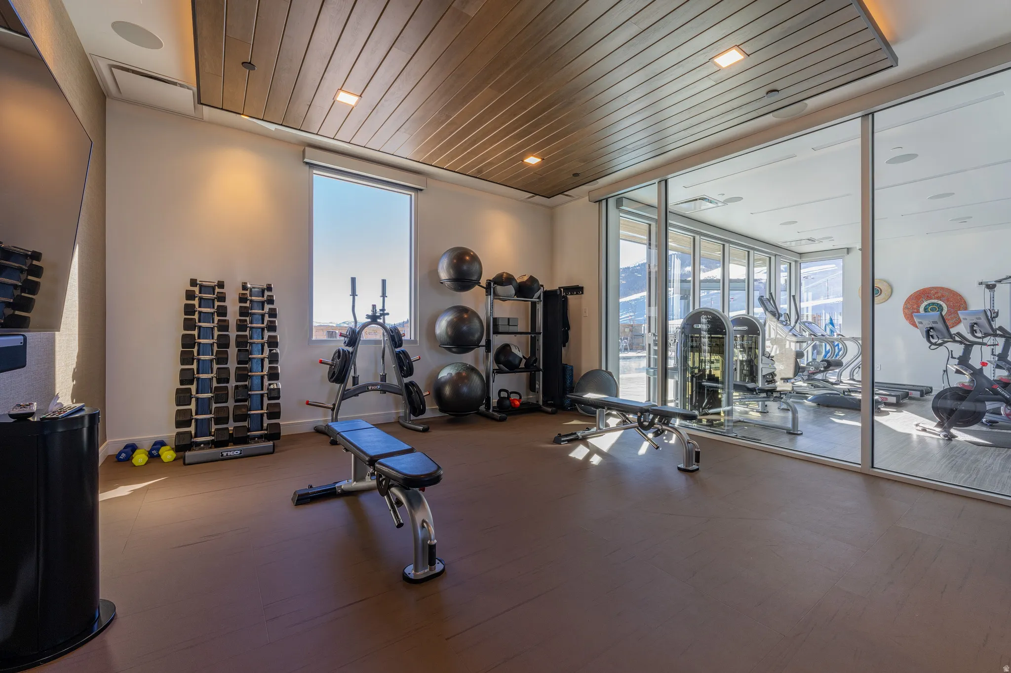 Dedicated exercise room featuring a wood-panel ceiling, recessed lighting, and a large window