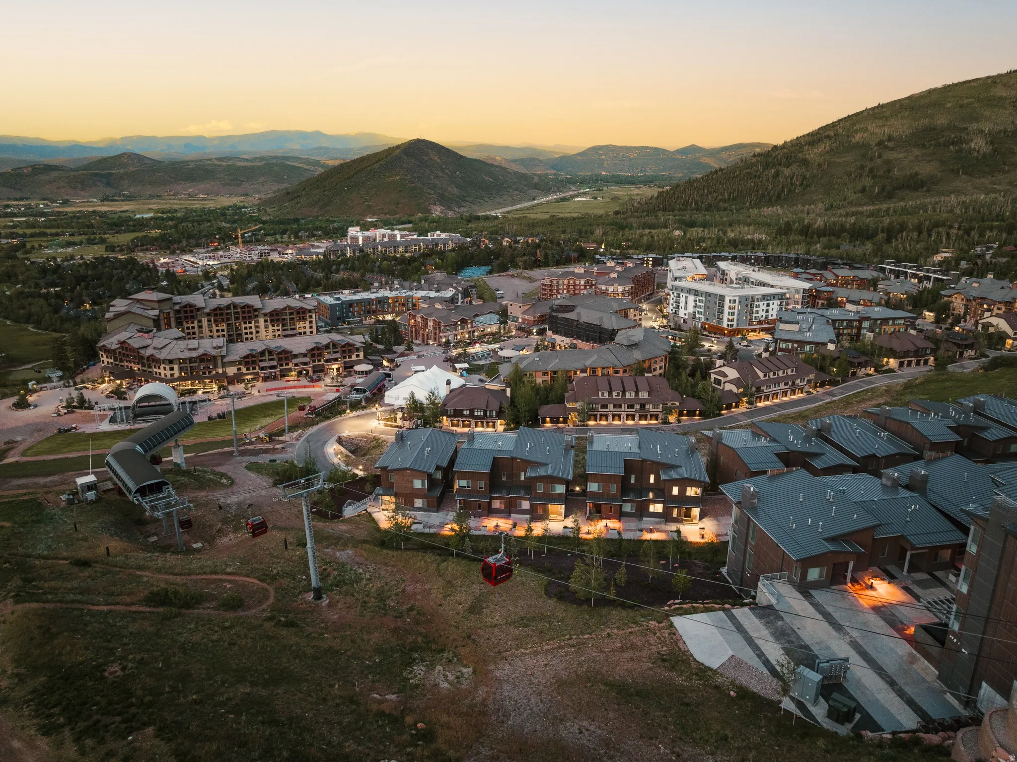 Aerial perspective showcasing an expansive community with diverse architectural styles, surrounded by mountainous terrain
