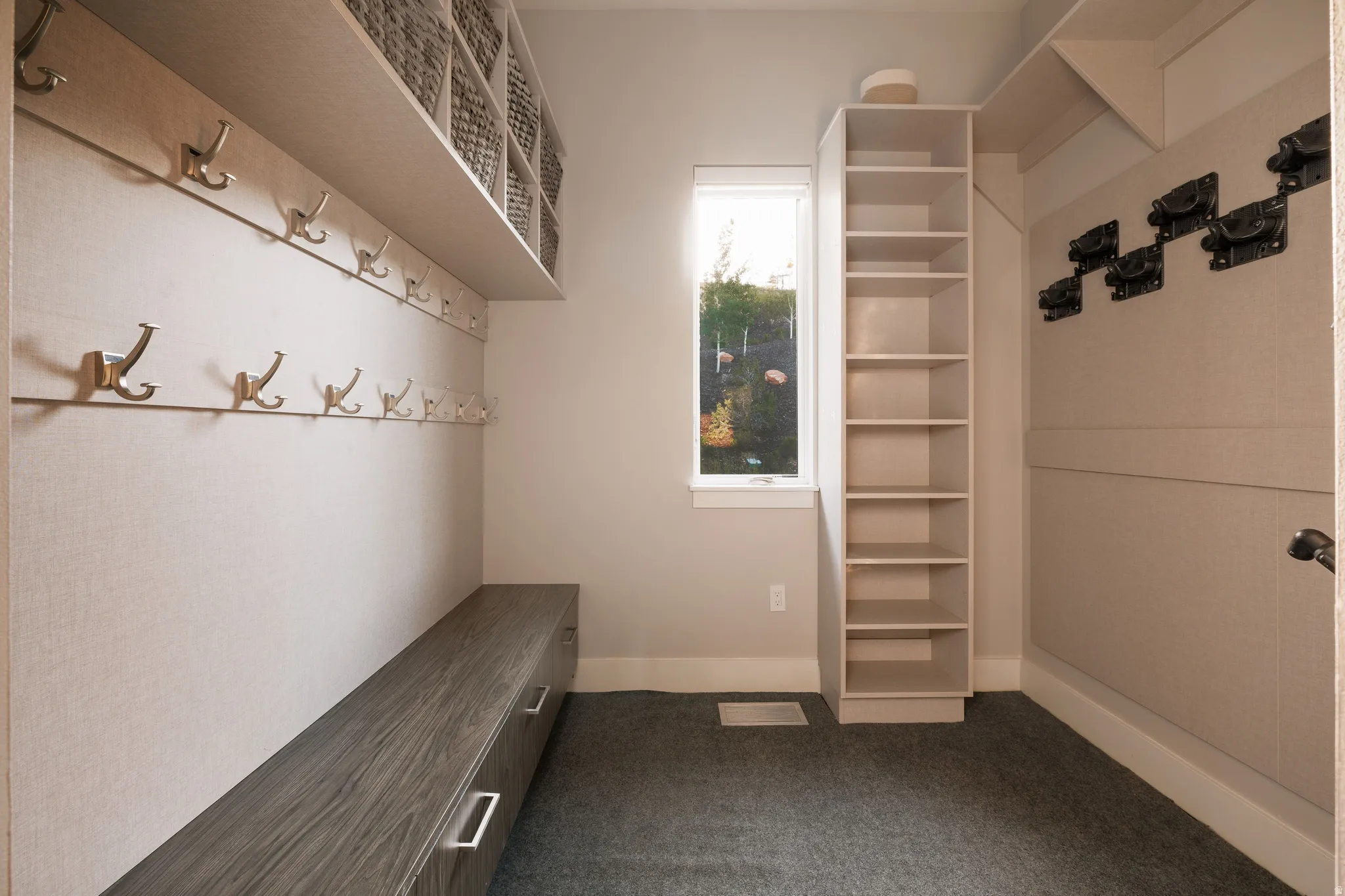 Built-in storage solutions featuring a wood-finish bench with integrated drawers, wall-mounted coat hooks, and open shelving