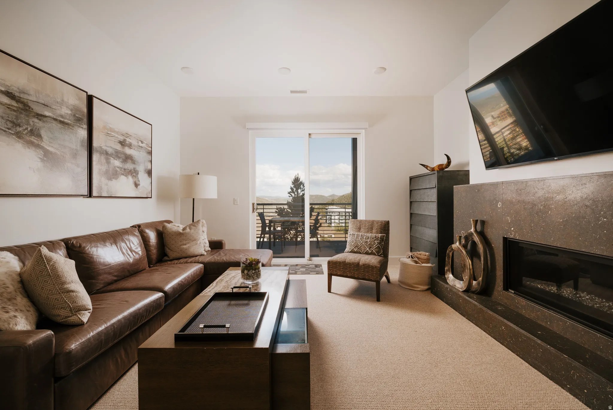 Living area featuring a stone-clad fireplace, recessed lighting, and sliding glass doors opening to an outdoor balcony