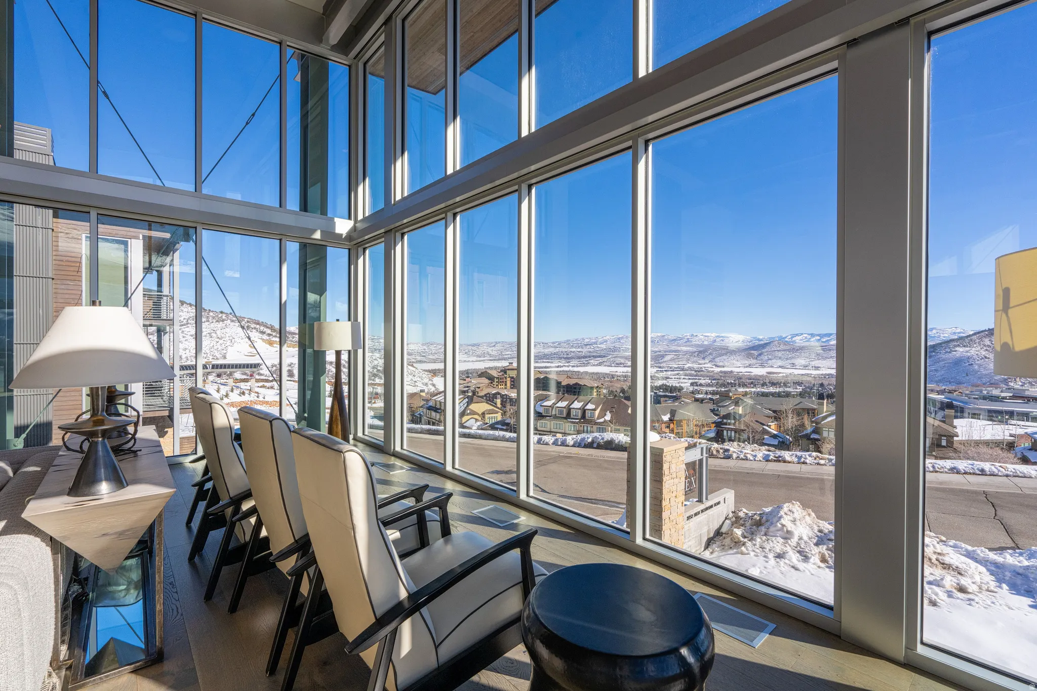 Expansive floor-to-ceiling windows with modern framing, showcasing panoramic mountain and neighborhood scenery