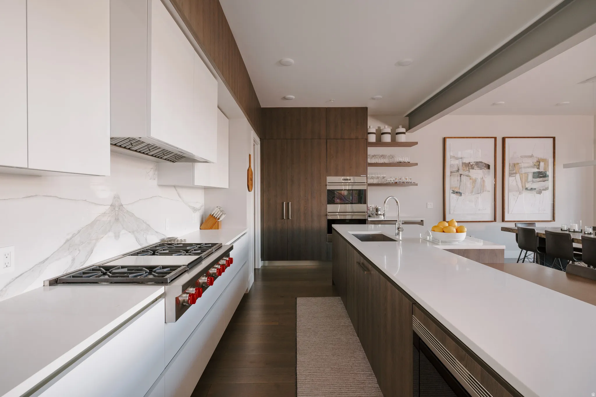Contemporary kitchen featuring a built-in range, white upper cabinetry, and a full-height marble-finish backsplash