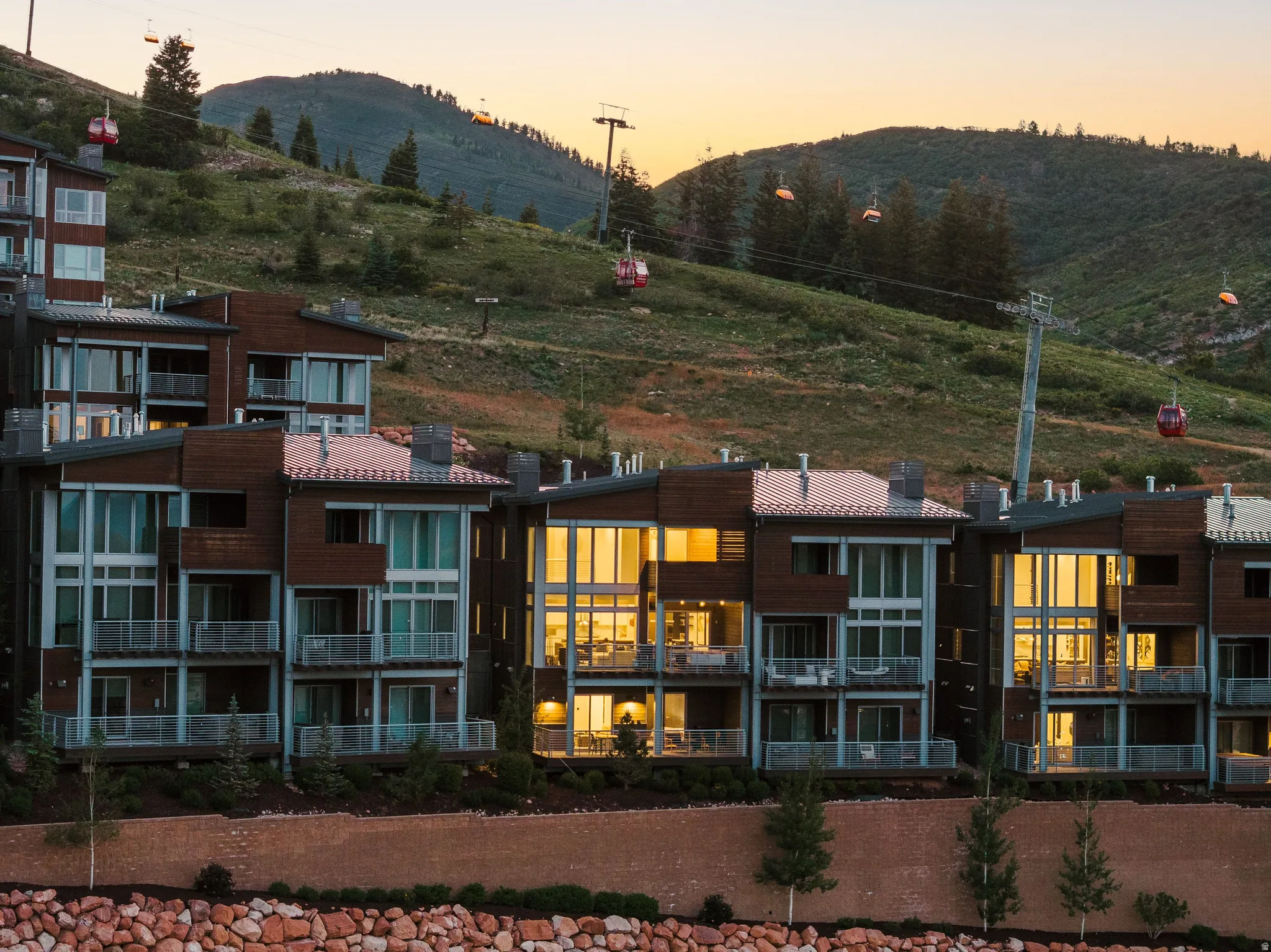 Contemporary multi-level residences featuring expansive window walls, private balconies with glass railings, and a rich wood and stucco exterior