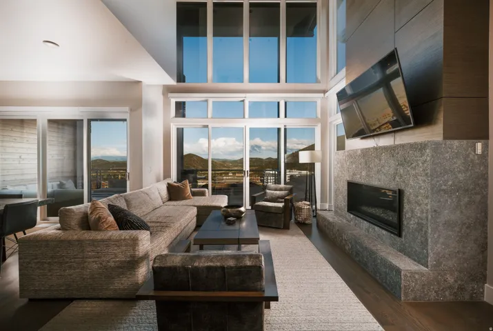 Spacious living area featuring a floor-to-ceiling stone fireplace, dark wood-finish flooring, and expansive sliding glass doors