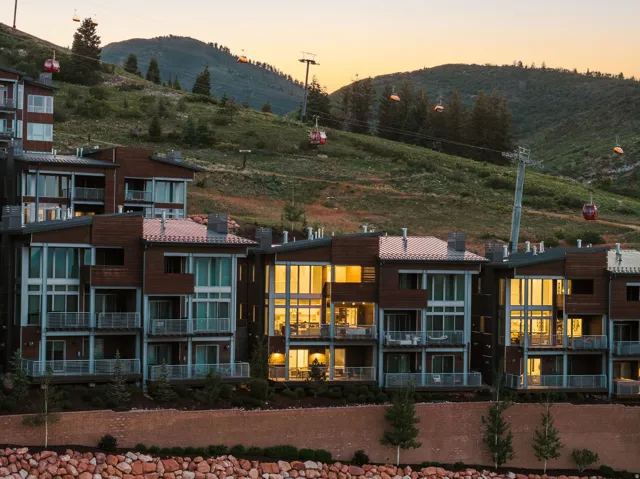 Contemporary multi-level residences featuring expansive window walls, private balconies with glass railings, and a rich wood and stucco exterior