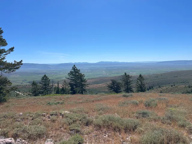 Expansive natural landscape featuring distant mountain ranges and a verdant valley below