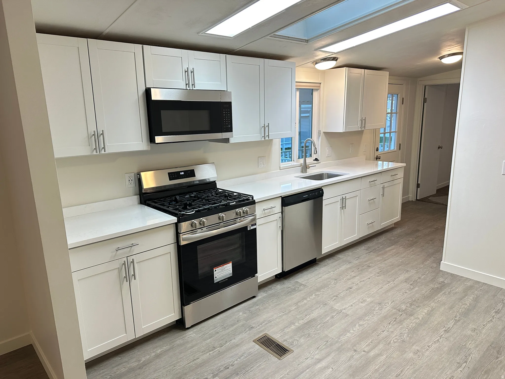 Modern kitchen featuring white shaker cabinetry, stainless steel appliances, and light-toned countertops